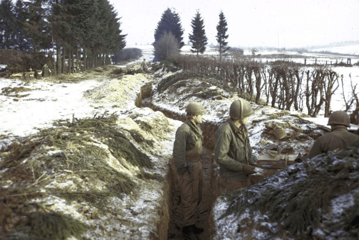 Американские солдаты занимают окопы вдоль заснеженной живой изгороди в северных Арденнских лесах во время битвы при Арденнах.
