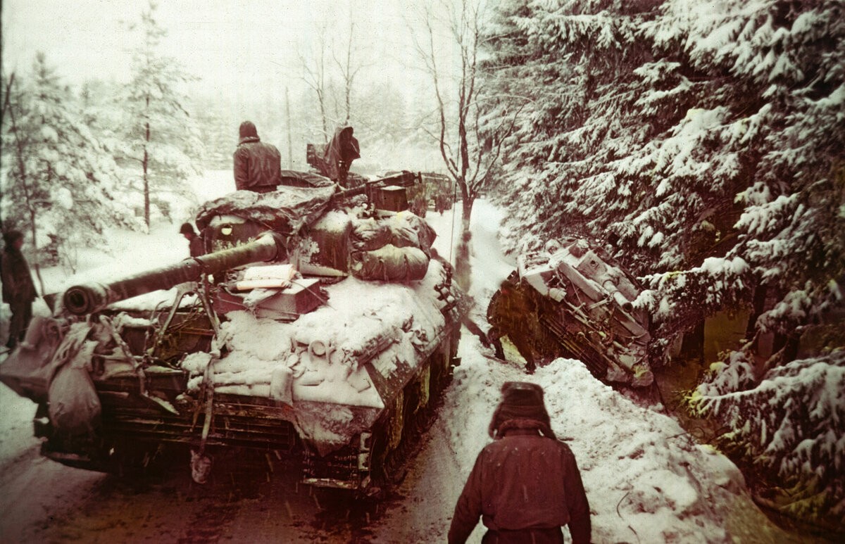 Американский танк проходит мимо другого, который соскользнул с обледенелой дороги в Арденнском лесу во время битвы за Балдж, 20 декабря 1944 года.